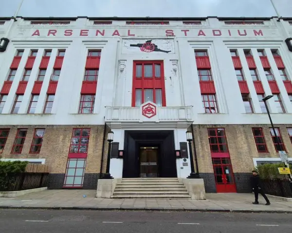 Dawny stadion Arsenalu w Highbury, z charakterystycznym napisem "ARSENAL STADIUM" i czerwonymi akcentami.