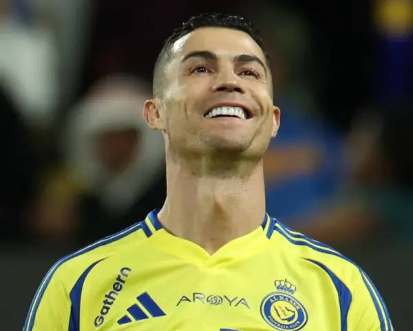 Uśmiechnięty Cristiano Ronaldo w żółtej koszulce Al Nassr. To właśnie w tym klubie gra Ronaldo.