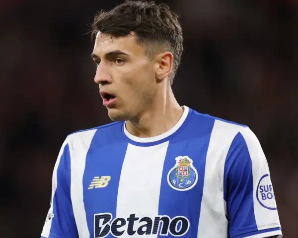 Piłkarz w niebiesko-białej koszulce FC Porto, gdzie gra Kiwior, z uwagą obserwuje boisko.
