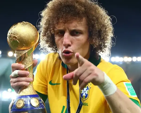 Piłkarz z Brazylii, z bujną fryzurą, triumfalnie trzyma złoty puchar Konfederacji FIFA.