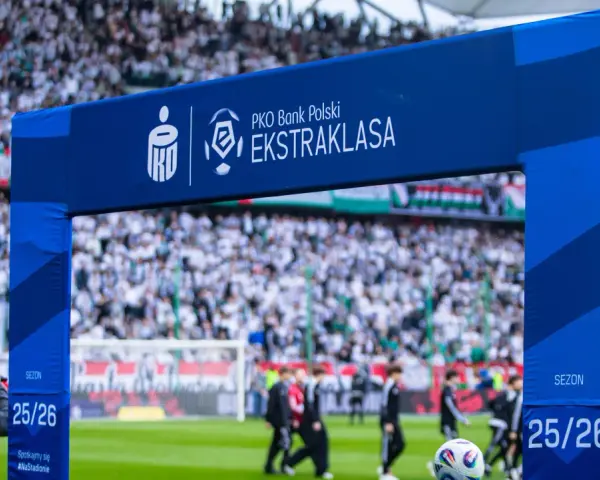 Brama z logo PKO Bank Polski Ekstraklasa na tle stadionu i kibiców. Sezon 25/26.