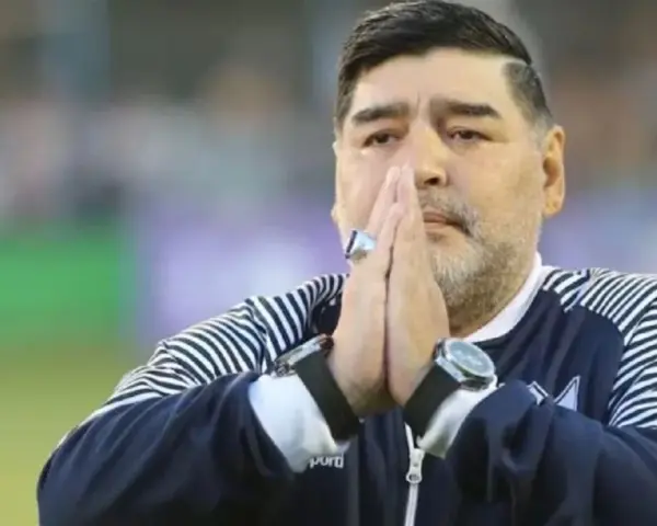 Diego Maradona na co zmarł? Legenda futbolu z dłońmi złożonymi do modlitwy, w charakterystycznej bluzie.