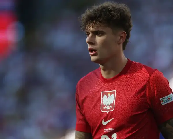 Młody piłkarz w czerwonej koszulce z orłem, symbolizujący polską reprezentację. Jego wzrost i determinacja na boisku budzą nadzieję na przyszłe sukcesy.