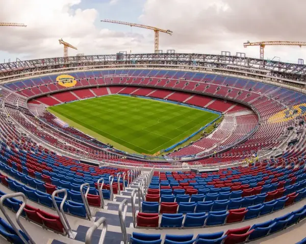 Stadion de la Cartuja w budowie, z widocznymi dźwigami i częściowo wykończonymi trybunami w kolorach czerwonym i niebieskim.