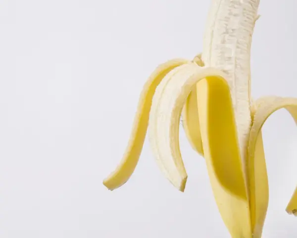 Połówka obranego banana, idealna przekąska przed czy po treningu, dostarcza energii.