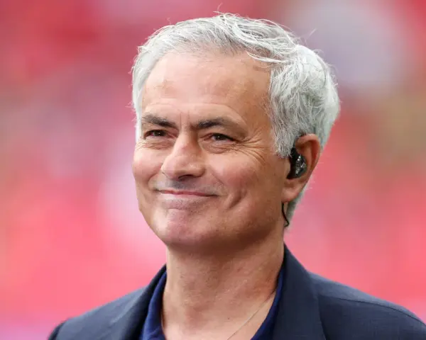 Uśmiechnięty José Mourinho, były trener Realu Madryt, z siwymi włosami i słuchawką w uchu.