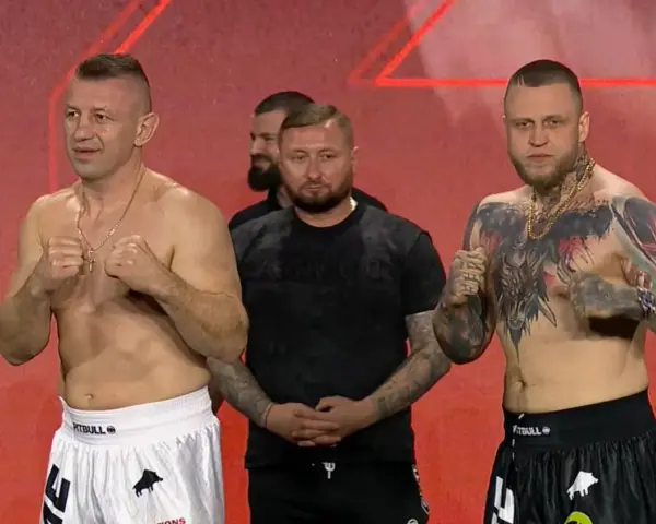 Dwóch zawodników MMA, jeden z tatuażami na klatce piersiowej, gotowych do walki. W tle stoi mężczyzna.