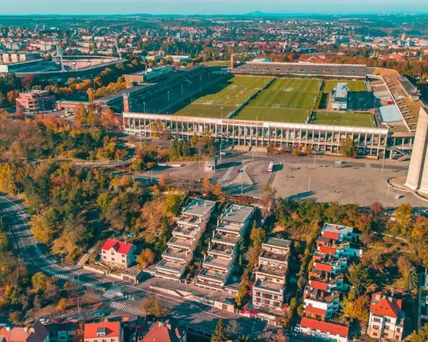 Widok z lotu ptaka na imponujący stadion, największy stadion w Europie, otoczony jesienną zielenią i nowoczesną zabudową.