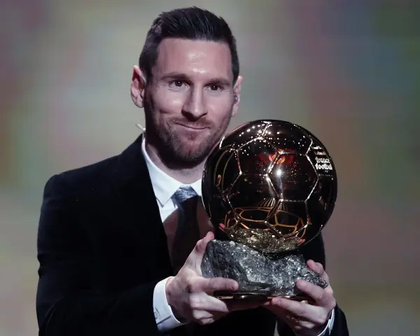Lionel Messi, który dostał Złotą Piłkę, prezentuje trofeum.