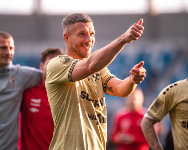Uśmiechnięty Lukas Podolski pokazuje kciuk w górę, jakby podsumowywał swoje świetne statystyki.