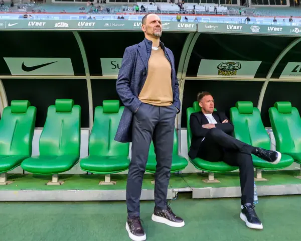 Trener Śląska Wrocław Ivan Djurdjevic stoi na tle zielonych siedzeń rezerwowych.