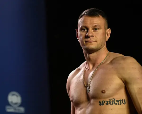 KSW relacja: Muskularny zawodnik MMA z tatuażem na klatce piersiowej pozuje przed kamerą.
