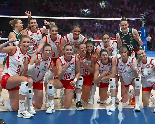Uśmiechnięte polskie siatkarki w biało-czerwonych strojach pozują do zdjęcia po meczu, dumne ze zwycięstwa.