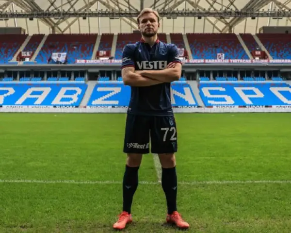 Piłkarz Tymek Puchacz w koszulce Trabzonspor z numerem 72, stoi na murawie stadionu.