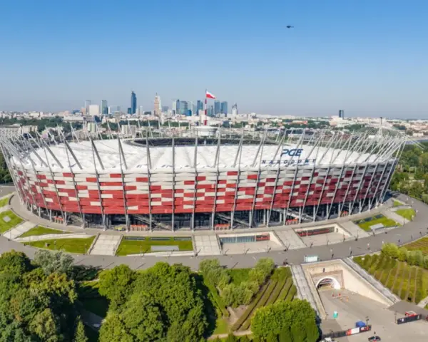 PGE Narodowy, jeden z największych stadionów w Polsce, w otoczeniu zieleni i warszawskiej panoramy.