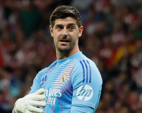 Bramkarz Realu Madryt, Thibaut Courtois, w jasnoniebieskiej koszulce z rękawicami, gotowy do obrony.