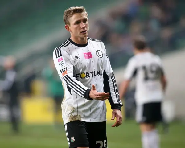Kuba Rzeźniczak w białej koszulce z czarnymi pasami, na boisku.
