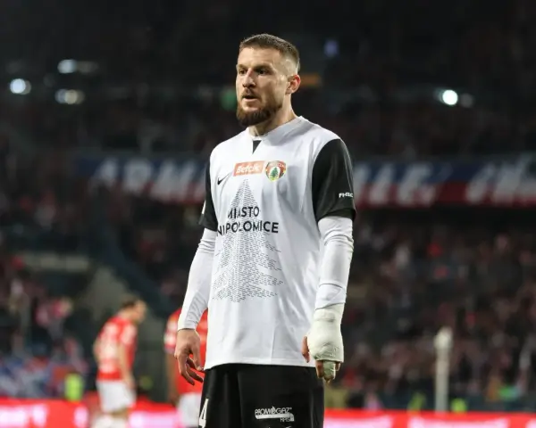Piłkarz w koszulce z napisem "Miasto Niepołomice" na tle trybun. Przebieg: Wisła Kraków – Puszcza Niepołomice.