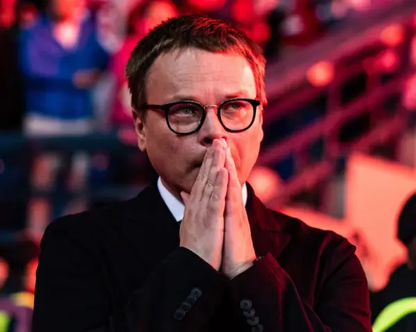 Właściciel Wisły Kraków, w okularach, z rękami złożonymi do modlitwy, wpatruje się w dal.