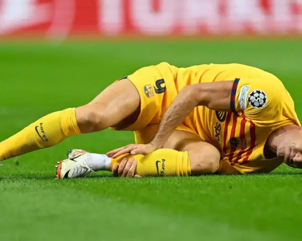 Piłkarz w żółtej koszulce leży na trawie, trzymając się za nogę. Wygląda na to, że Robert Lewandowski kontuzja uniemożliwiła mu dalszą grę.