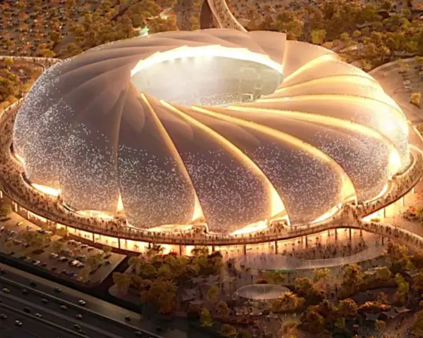 Futurystyczny stadion, który może być najładniejszy na świecie, z falującym dachem i oświetlonymi detalami, otoczony zielenią i tłumem ludzi.