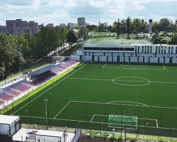 Nowy stadion Polonii Bytom z zieloną murawą, trybunami w kolorach czerwonym i niebieskim oraz nowoczesnym budynkiem klubowym.