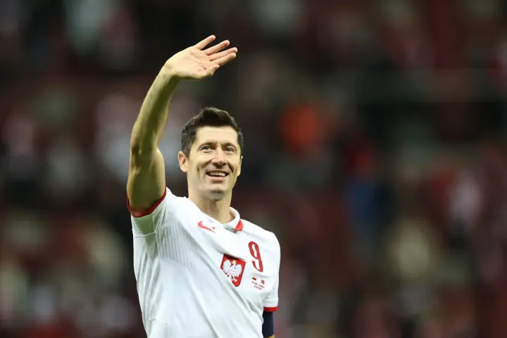 Robert Lewandowski w koszulce reprezentacji Polski z numerem 9, macha do kibiców.