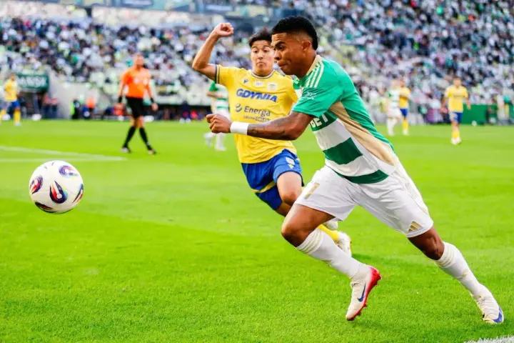 Piłkarz Lechii Gdańsk w zielono-białej koszulce biegnie z piłką, ścigany przez zawodnika Arki Gdynia. Mecz składy: Arka Gdynia – Lechia Gdańsk.