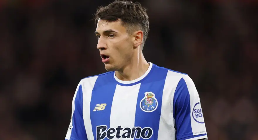 Piłkarz w niebiesko-białej koszulce FC Porto, gdzie gra Kiwior, z uwagą obserwuje boisko.