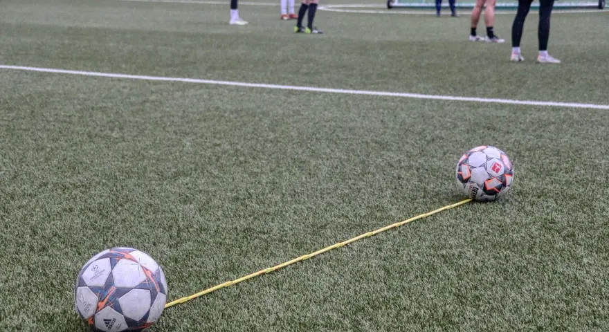Dwa piłki na boisku połączone żółtą linką. Trening, który pokazuje, jak nie być profesjonalnym piłkarzem.