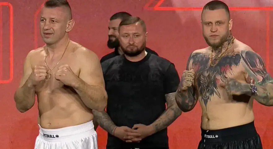 Dwóch zawodników MMA, jeden z tatuażami na klatce piersiowej, gotowych do walki. W tle stoi mężczyzna.