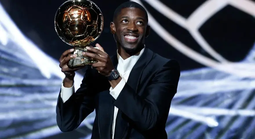Piłkarz Ousmane Dembélé trzyma Złotą Piłkę na scenie.