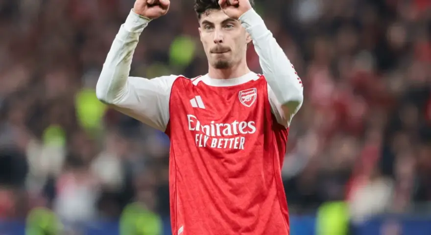 Piłkarz Arsenalu świętuje klasyczny hattrick, wznosząc pięści w geście triumfu na tle trybun.
