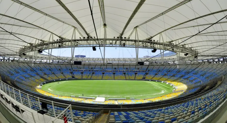 Pusta Marakana, stadion w Rio de Janeiro, z zieloną murawą i żółto-niebieskimi siedzeniami pod białym dachem.