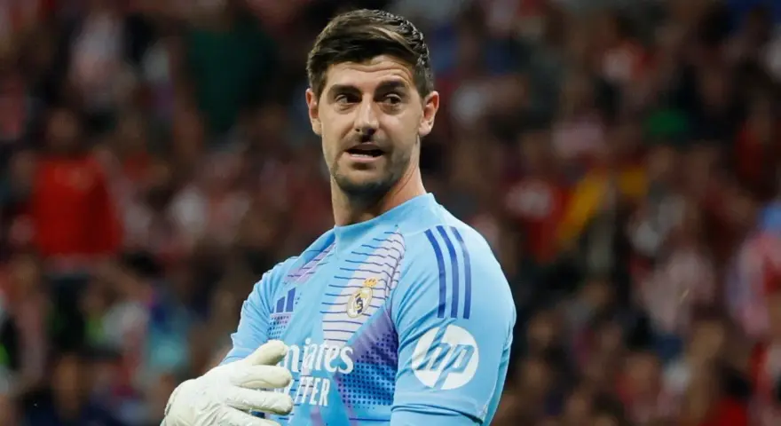 Bramkarz Realu Madryt, Thibaut Courtois, w jasnoniebieskiej koszulce z rękawicami, gotowy do obrony.