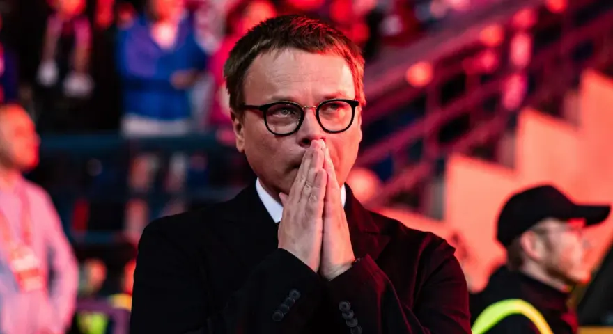 Właściciel Wisły Kraków, w okularach, z rękami złożonymi do modlitwy, wpatruje się w dal.