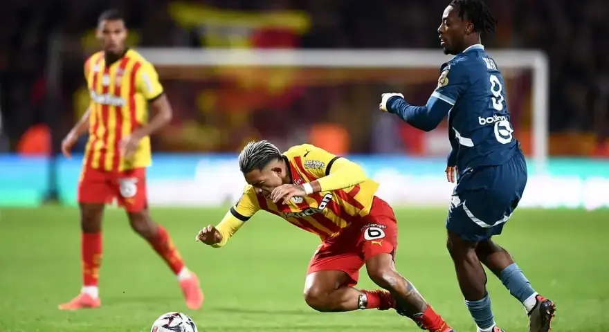 Piłkarz RC Lens w żółto-czerwonym stroju walczy o piłkę z zawodnikiem Stade Rennais.