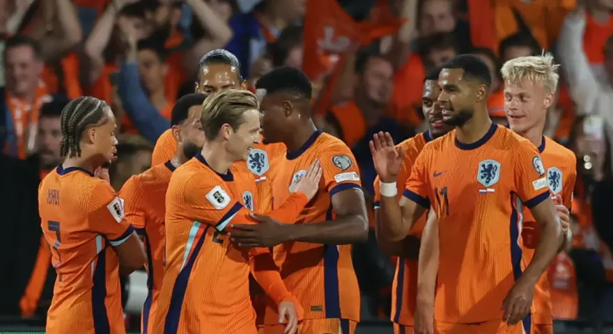Piłkarze Holandii w pomarańczowych strojach świętują zwycięstwo. Widać radość i jedność drużyny, symbolizującą siłę narodową.