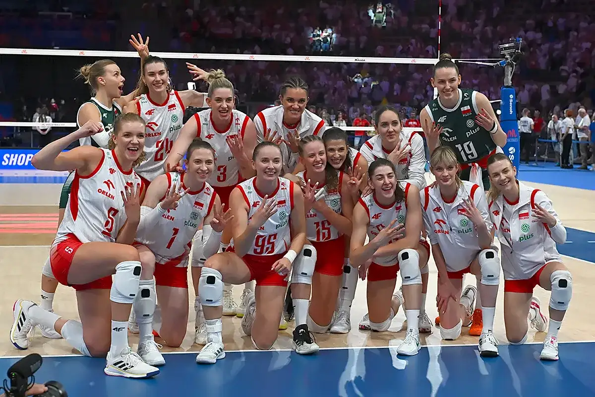 Uśmiechnięte polskie siatkarki w biało-czerwonych strojach pozują do zdjęcia po meczu, dumne ze zwycięstwa.