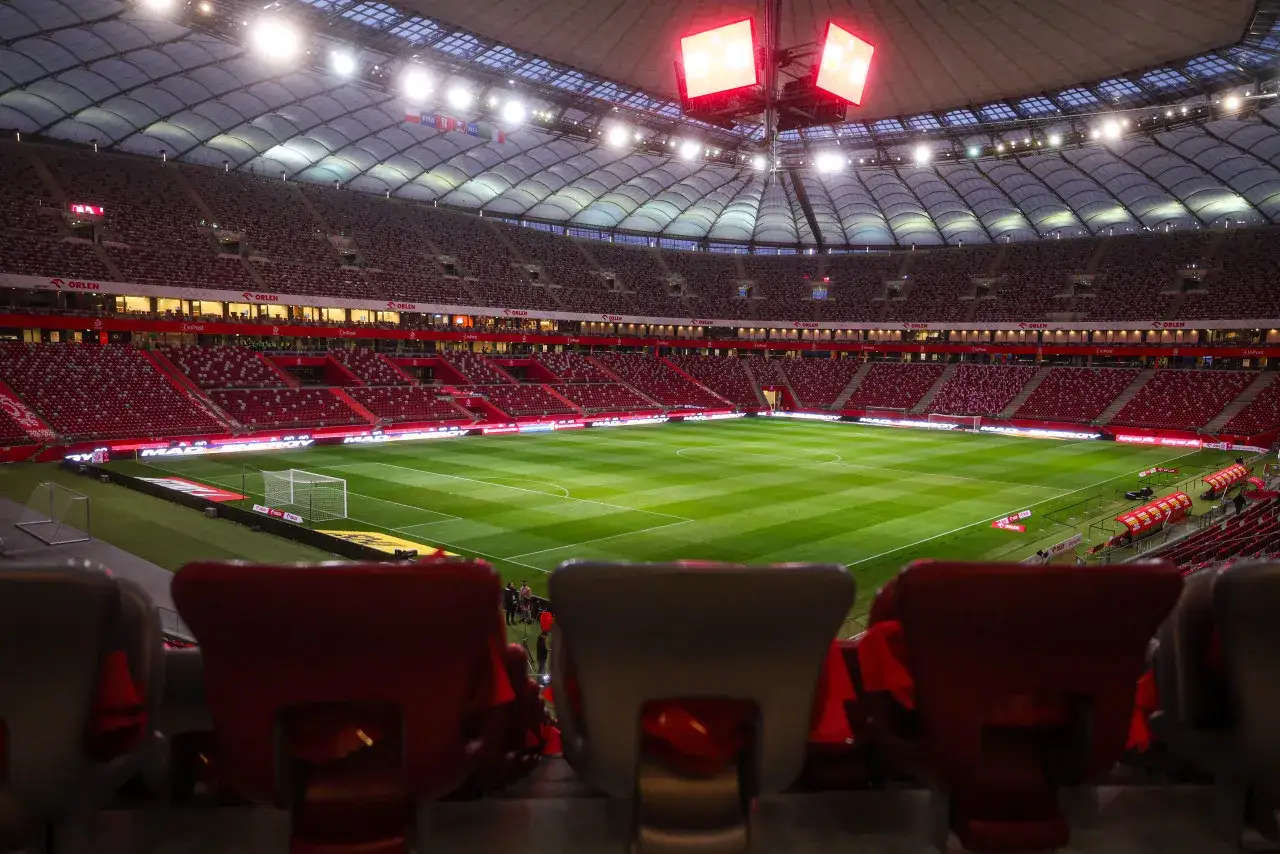 Pusta trybuna stadionu, zielona murawa i bramka czekają na emocje, kiedy liga mistrzów 2026.