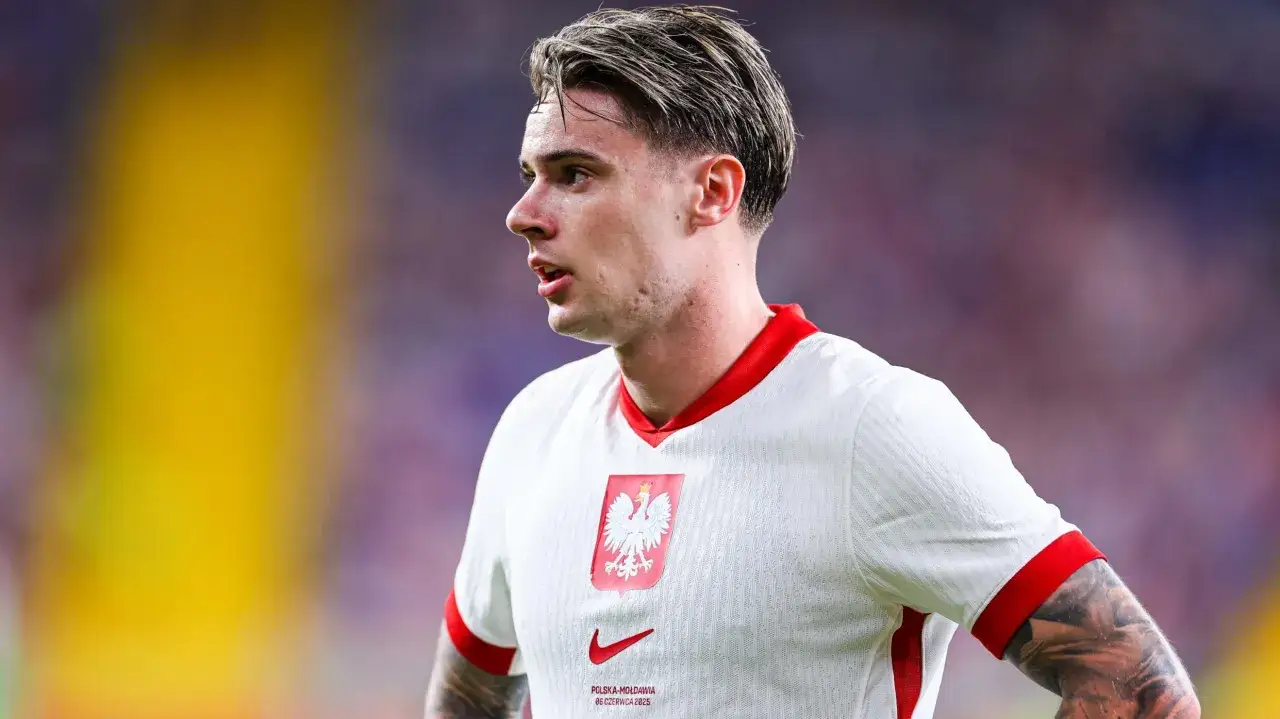 Piłkarz reprezentacji Polski, Nicola Zalewski, w białej koszulce z orłem. Jego wiek nie jest widoczny, ale skupienie na twarzy mówi wiele.