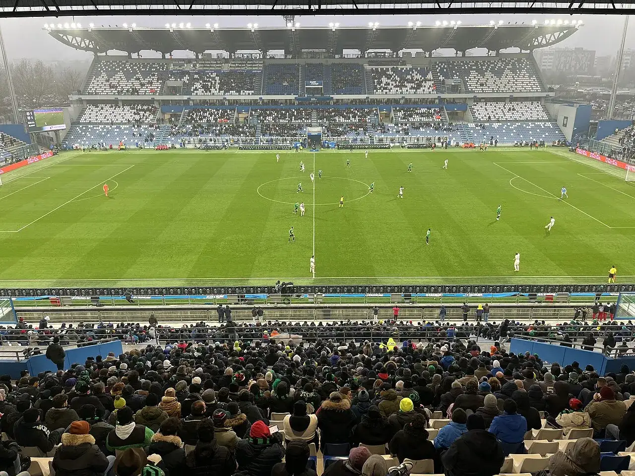 Widok z trybun na mecz piłki nożnej. Na boisku trwa przebieg: Inter Mediolan – Sassuolo. Kibice oglądają grę.