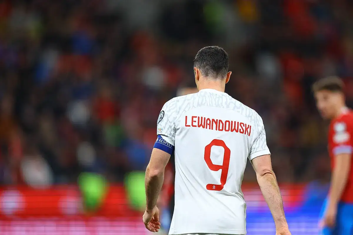 Piłkarz Robert Lewandowski w białej koszulce z numerem 9. Na plecach widnieje napis