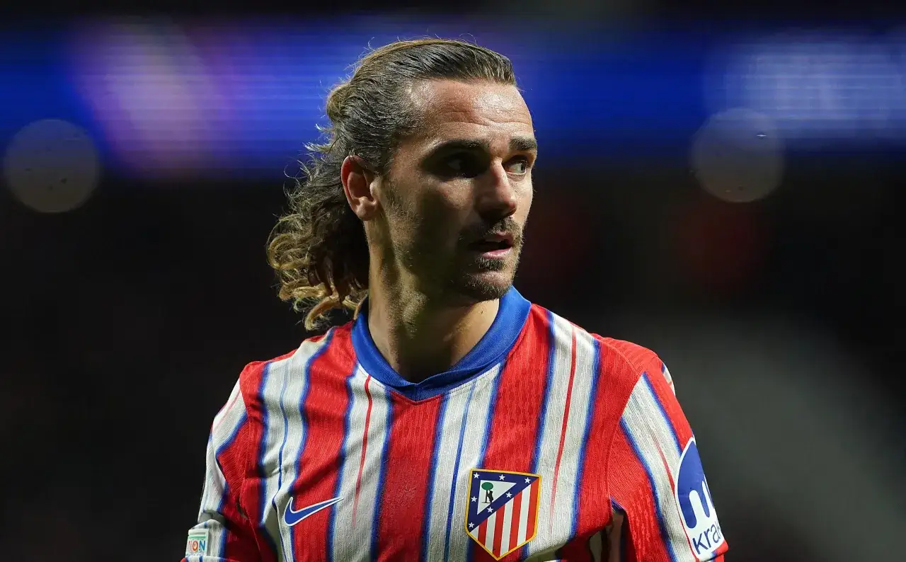 Grizman w czerwono-białej koszulce Atletico Madryt, z charakterystyczną fryzurą, gotowy do gry.