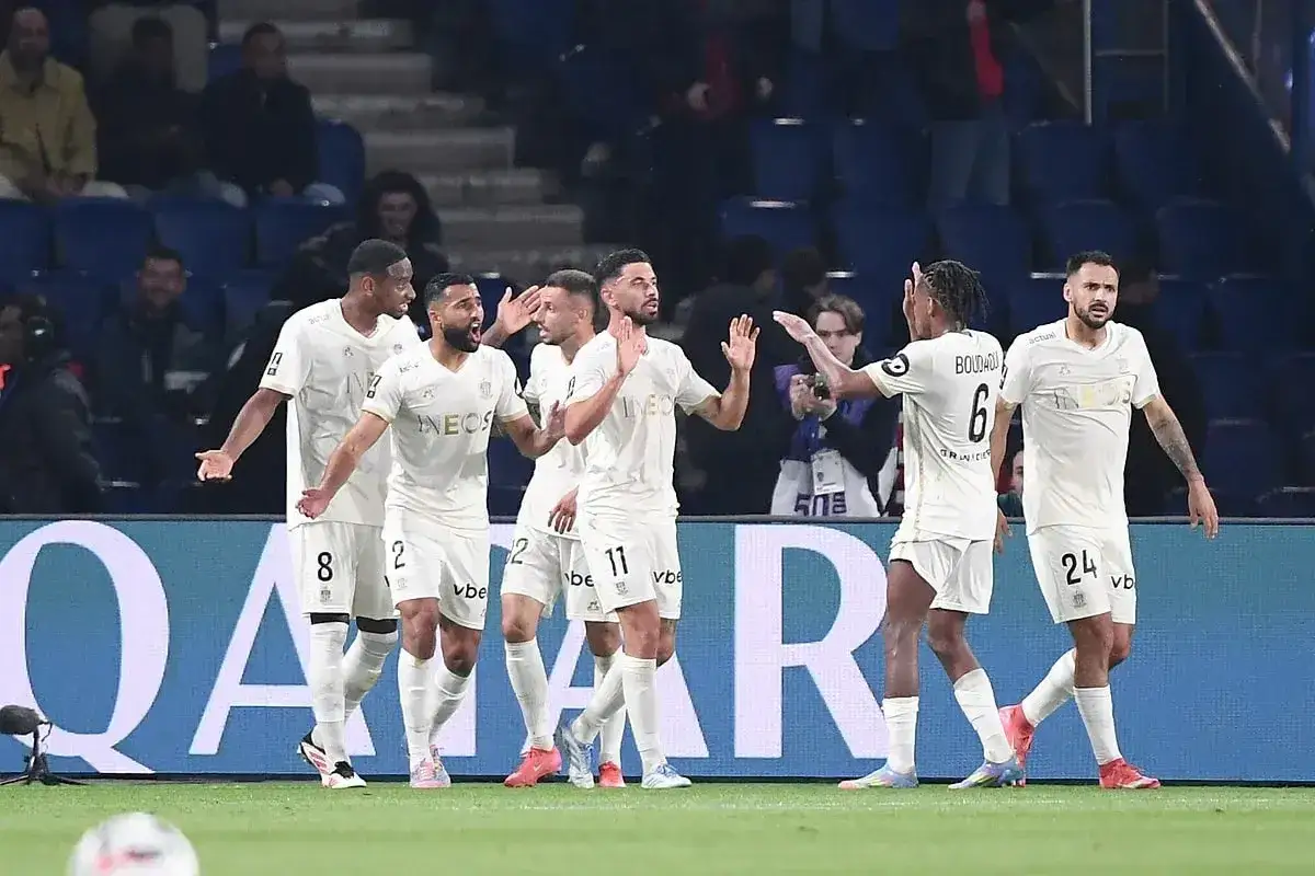 Piłkarze OGC Nice świętują bramkę przeciwko Stade de Reims. Drużyna w białych strojach cieszy się z sukcesu na boisku.