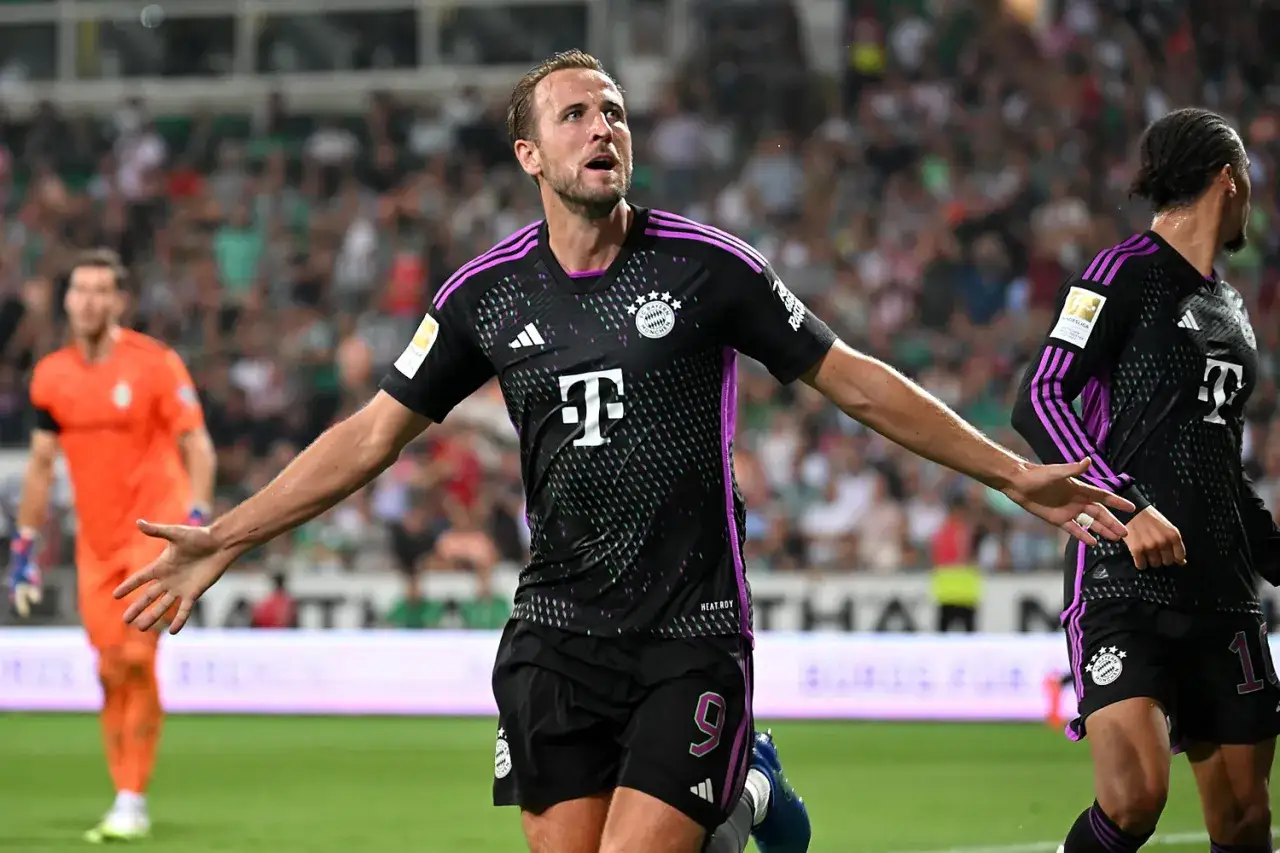 Piłkarz Harry Kane w czarnej koszulce z fioletowymi pasami, z numerem 9, cieszy się po golu. Ciekawe, ile zarabia Harry Kane za takie emocje!