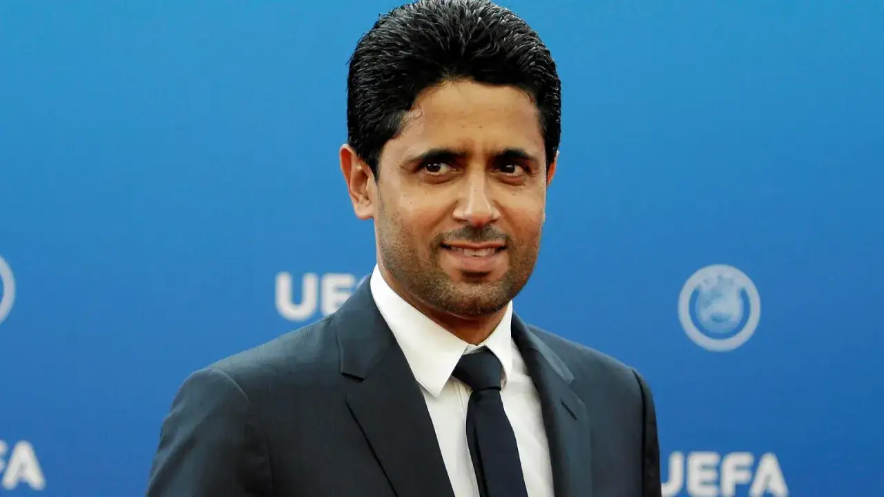 Nasser Al-Khelaifi, właściciel PSG, w garniturze na tle niebieskiej ścianki z logo UEFA.