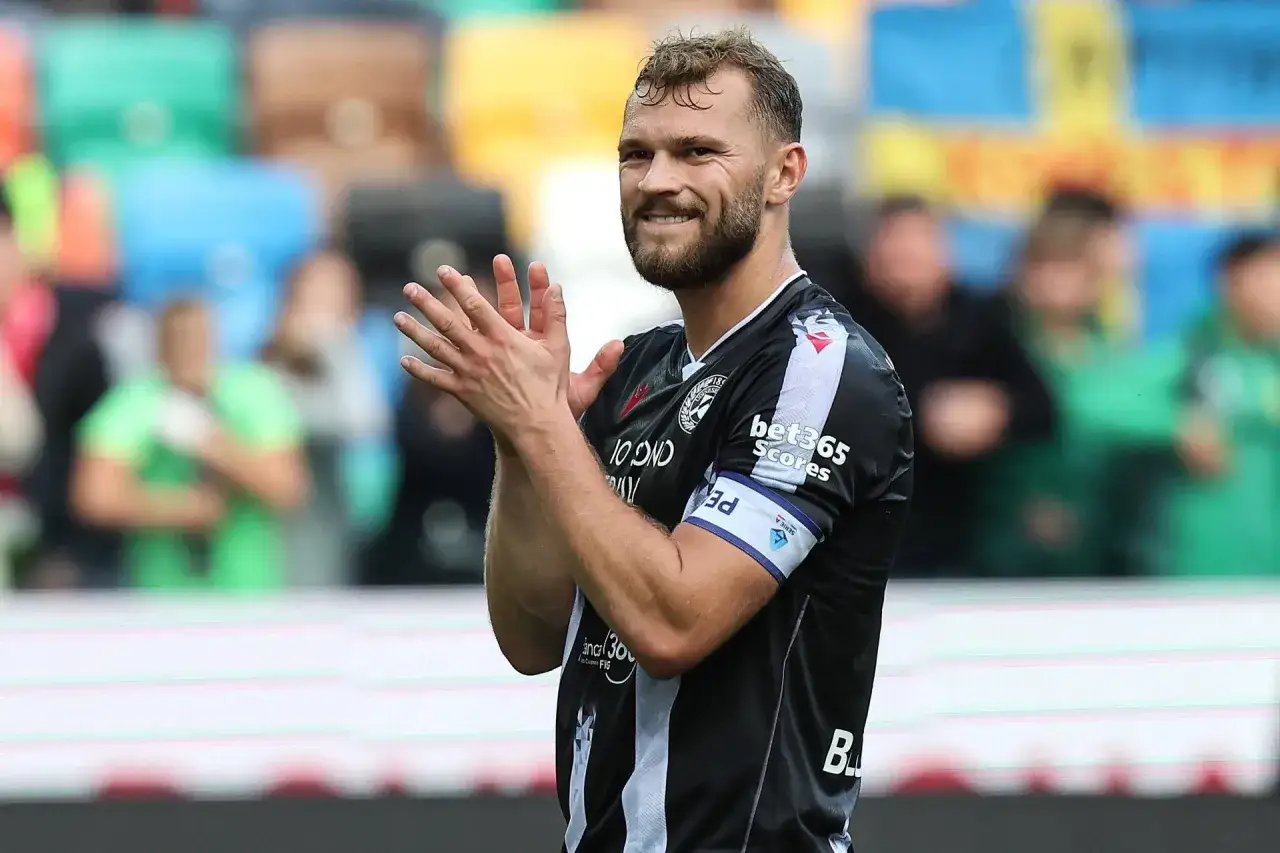Uśmiechnięty Jesper Karlström, kapitan drużyny, klaszcze na boisku.