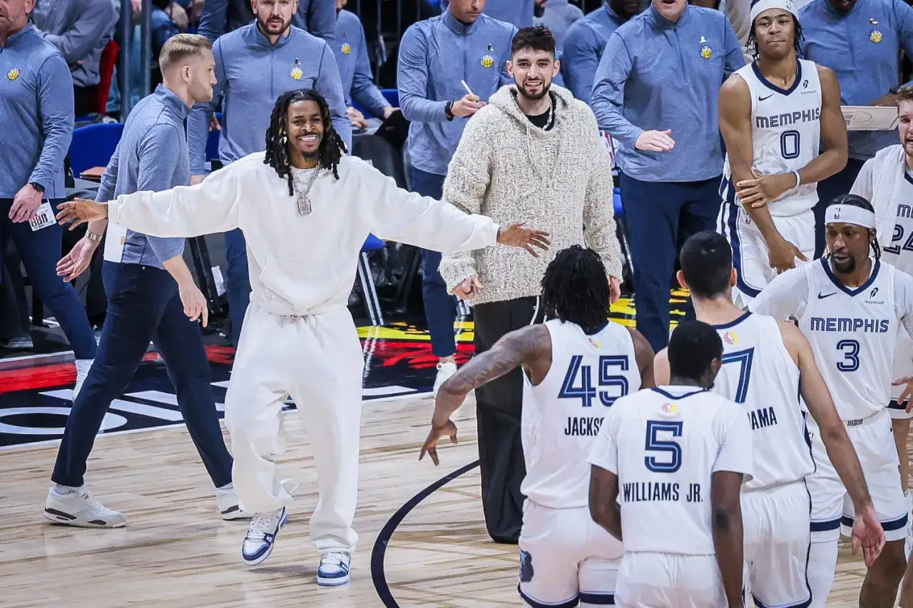 Uśmiechnięty zawodnik w białym dresie, z łańcuchem na szyi, wita się z drużyną Memphis.