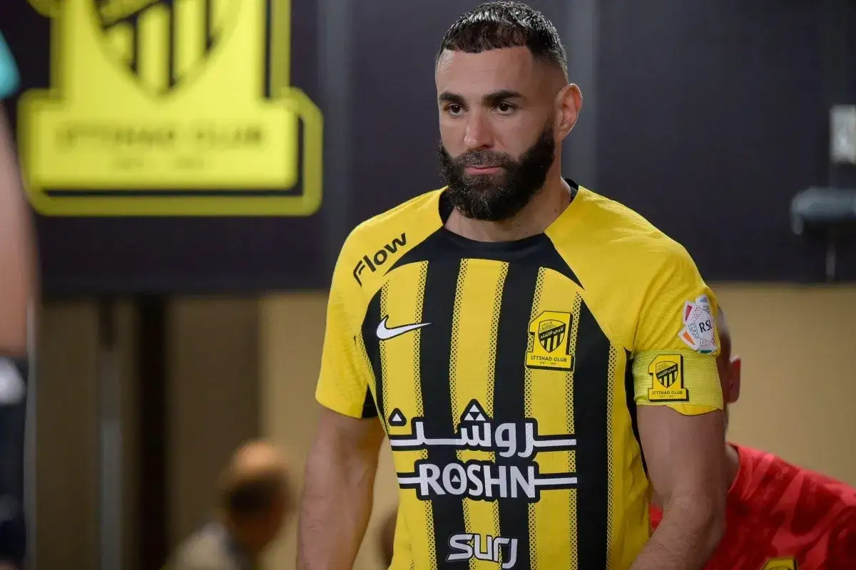 Karim Benzema w żółtej koszulce z czarnymi pasami, zastanawia się, ile zarabia.
